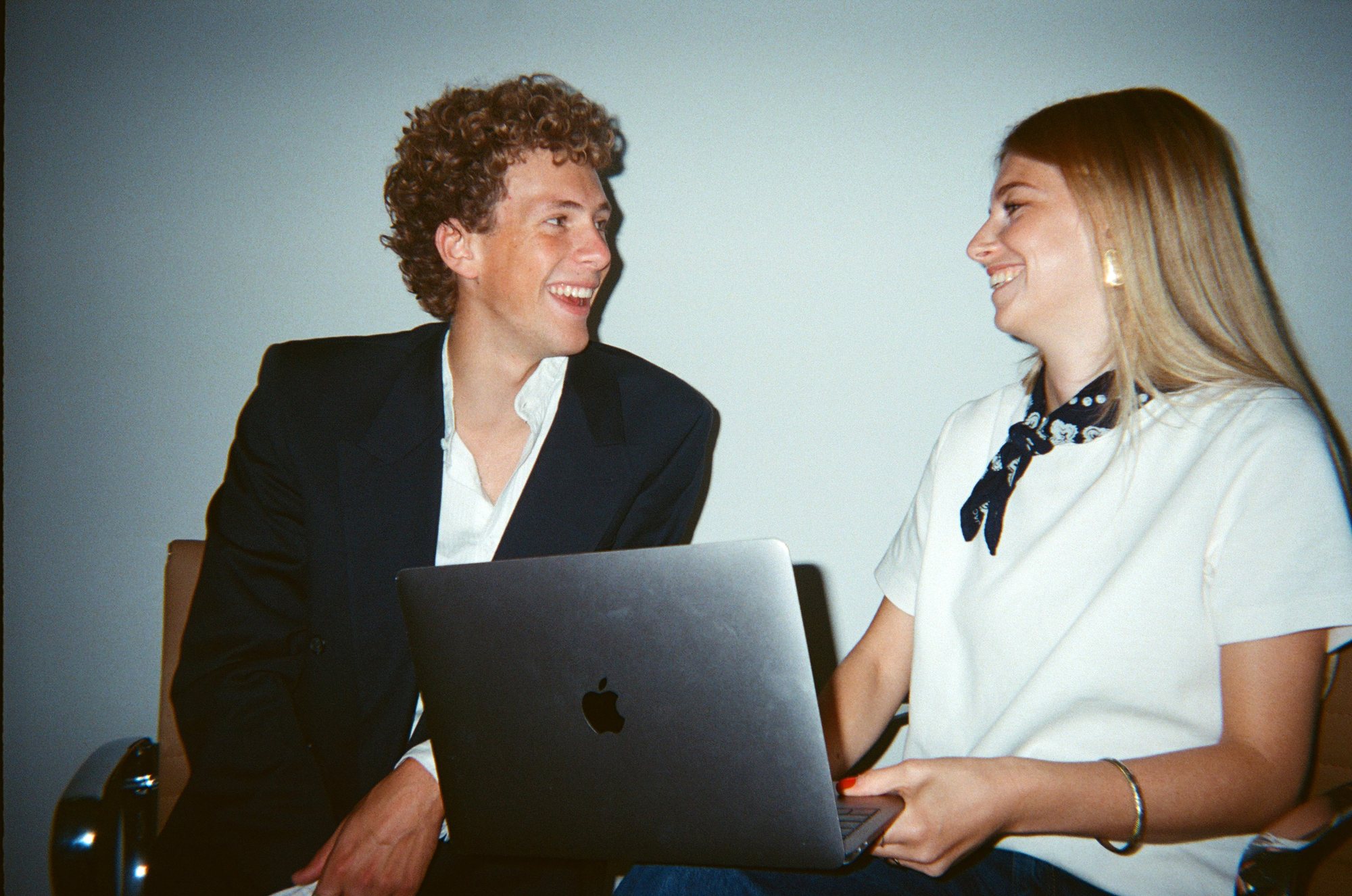 Two colleagues laughing while talking at a laptop