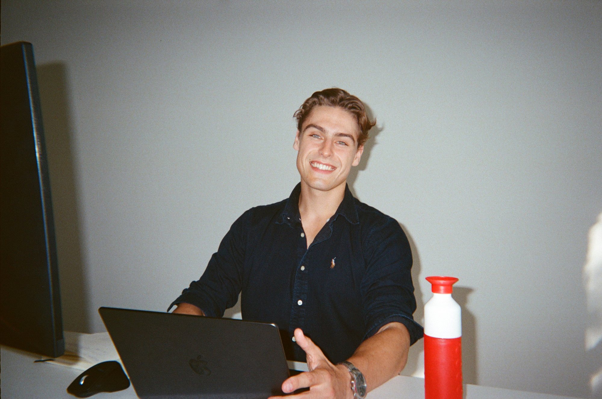Young professional laughing behind his laptop